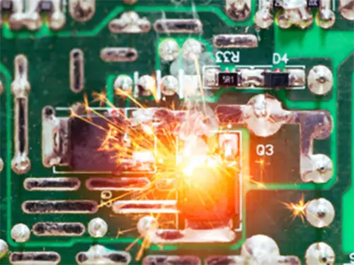 Close-up of burnt electronics on a circuit board, highlighting damage caused by electrical failure.