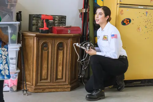 electrican working on a whole home surge protector in garage