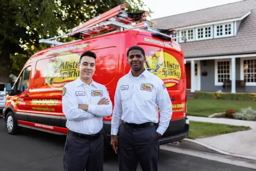Emilio and a Mister Sparky team member standing next to a red service van in Tampa. Circuit Repair